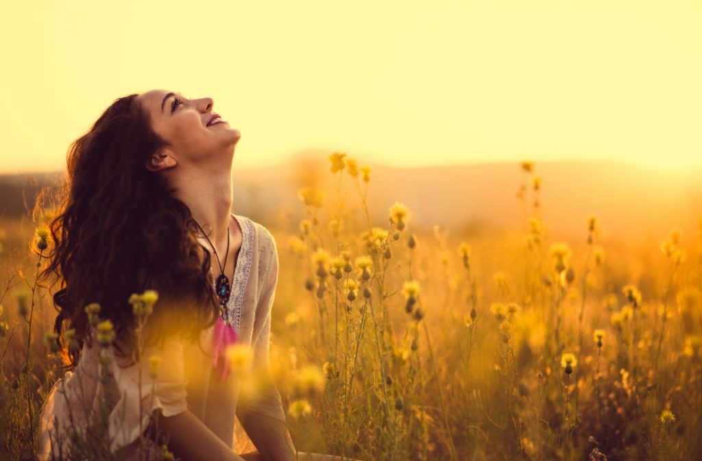 Happy lady in a field looking up at reiki energy
